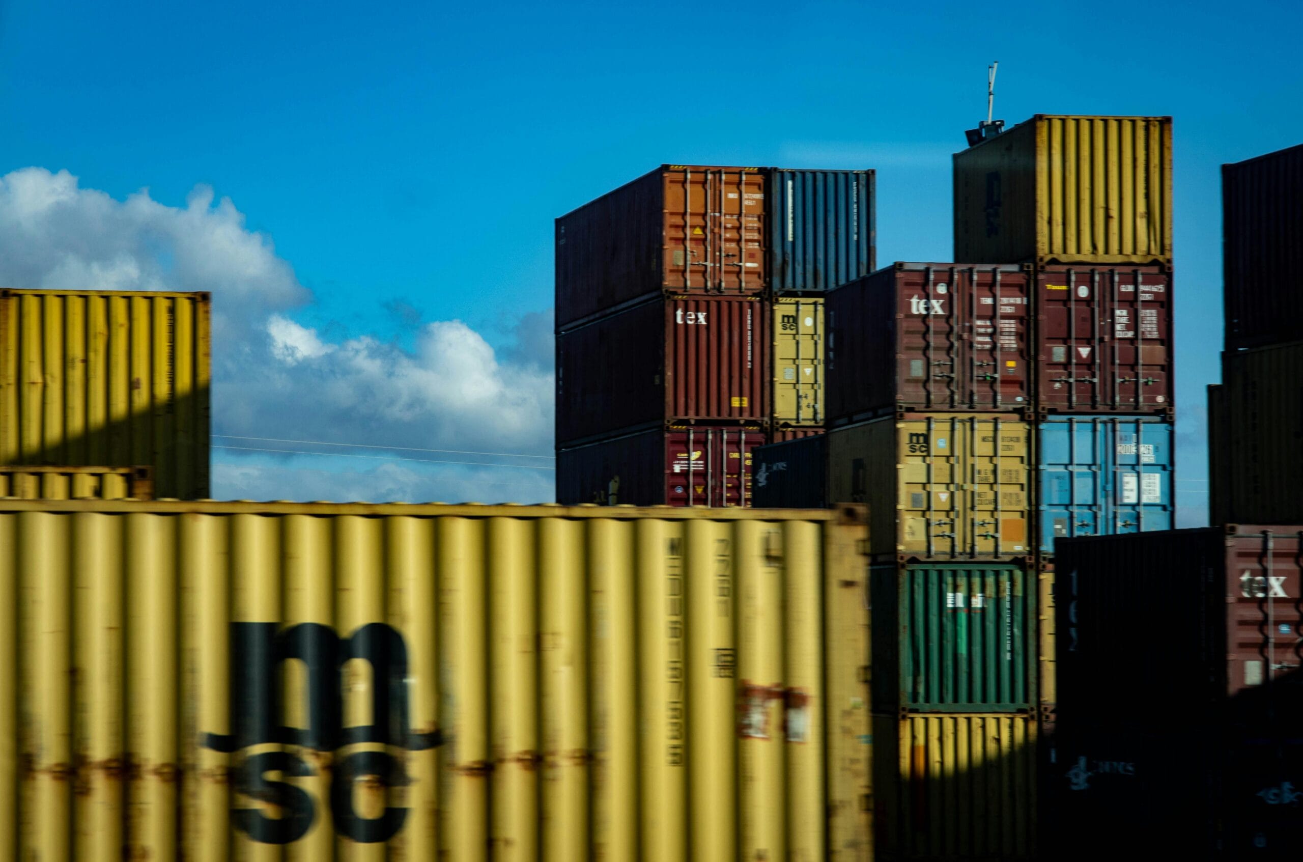 A vibrant display of stacked cargo containers against a clear blue sky.